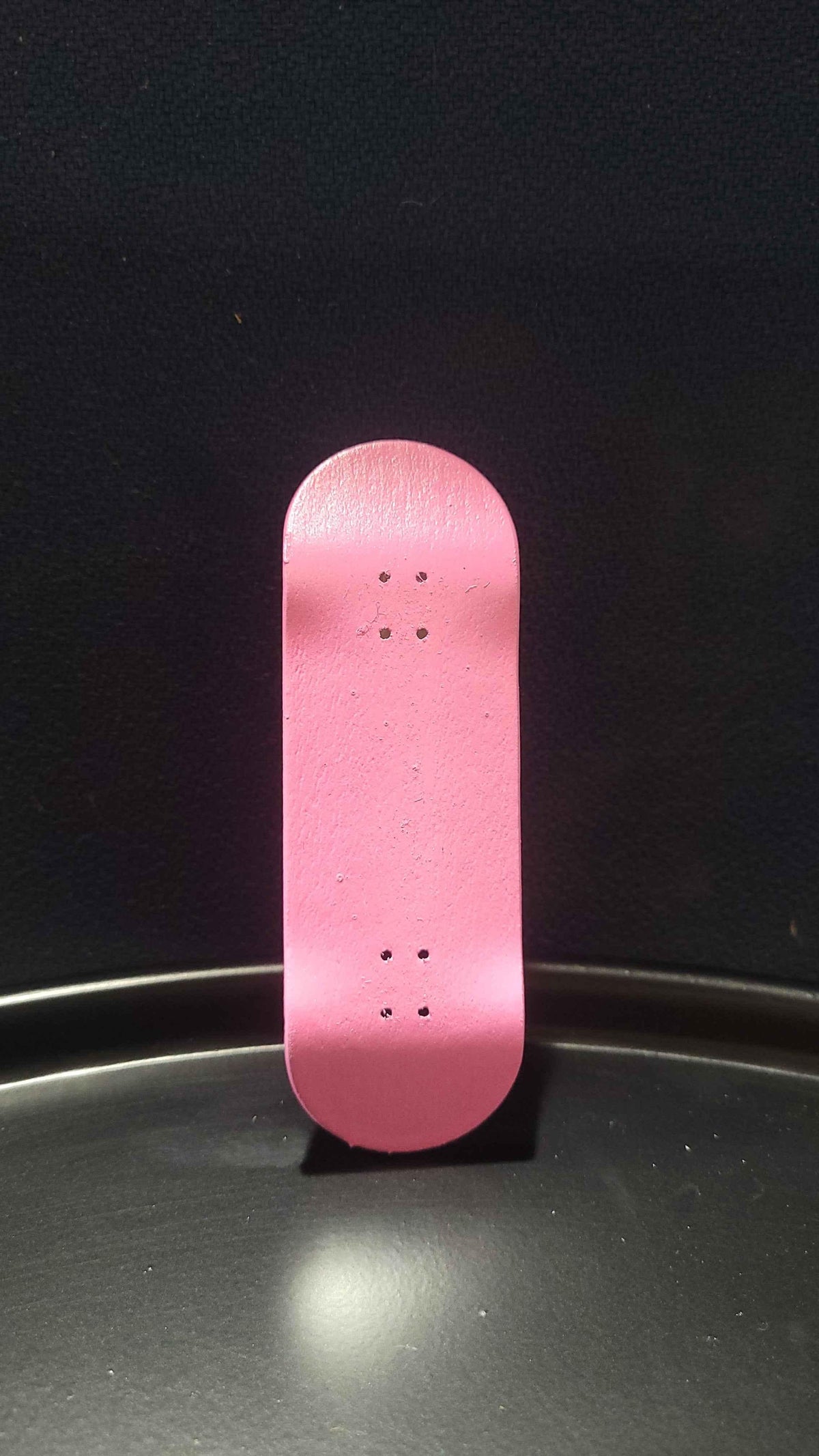 Pink handmade custom fingerboard deck on a dark background