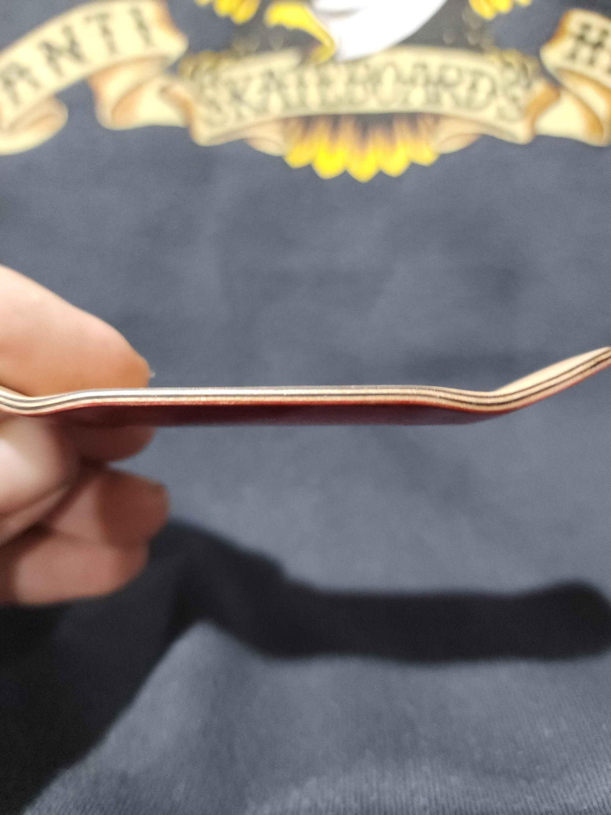 Side view of a professional handmade fingerboard deck showing the concave profile
