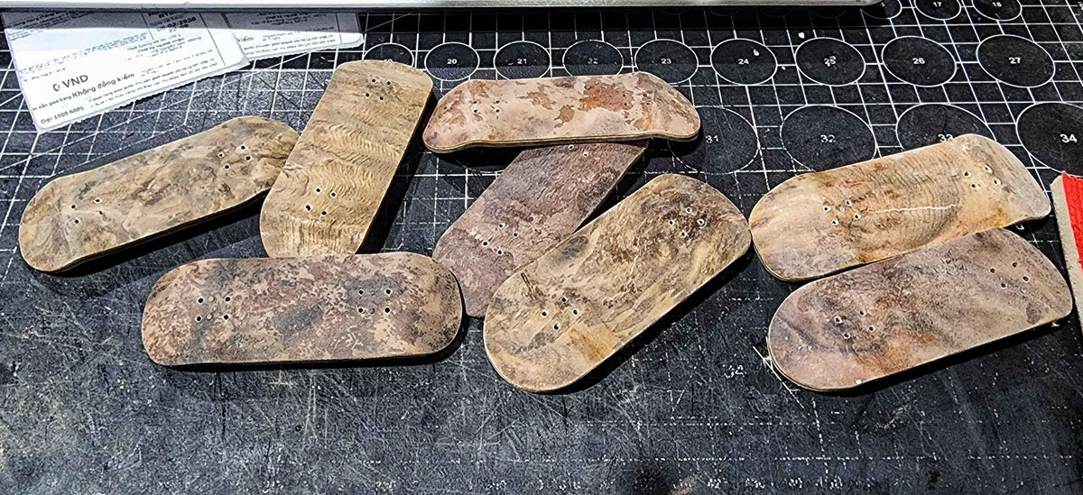 Assorted handmade custom wooden fingerboard decks on a cutting mat.