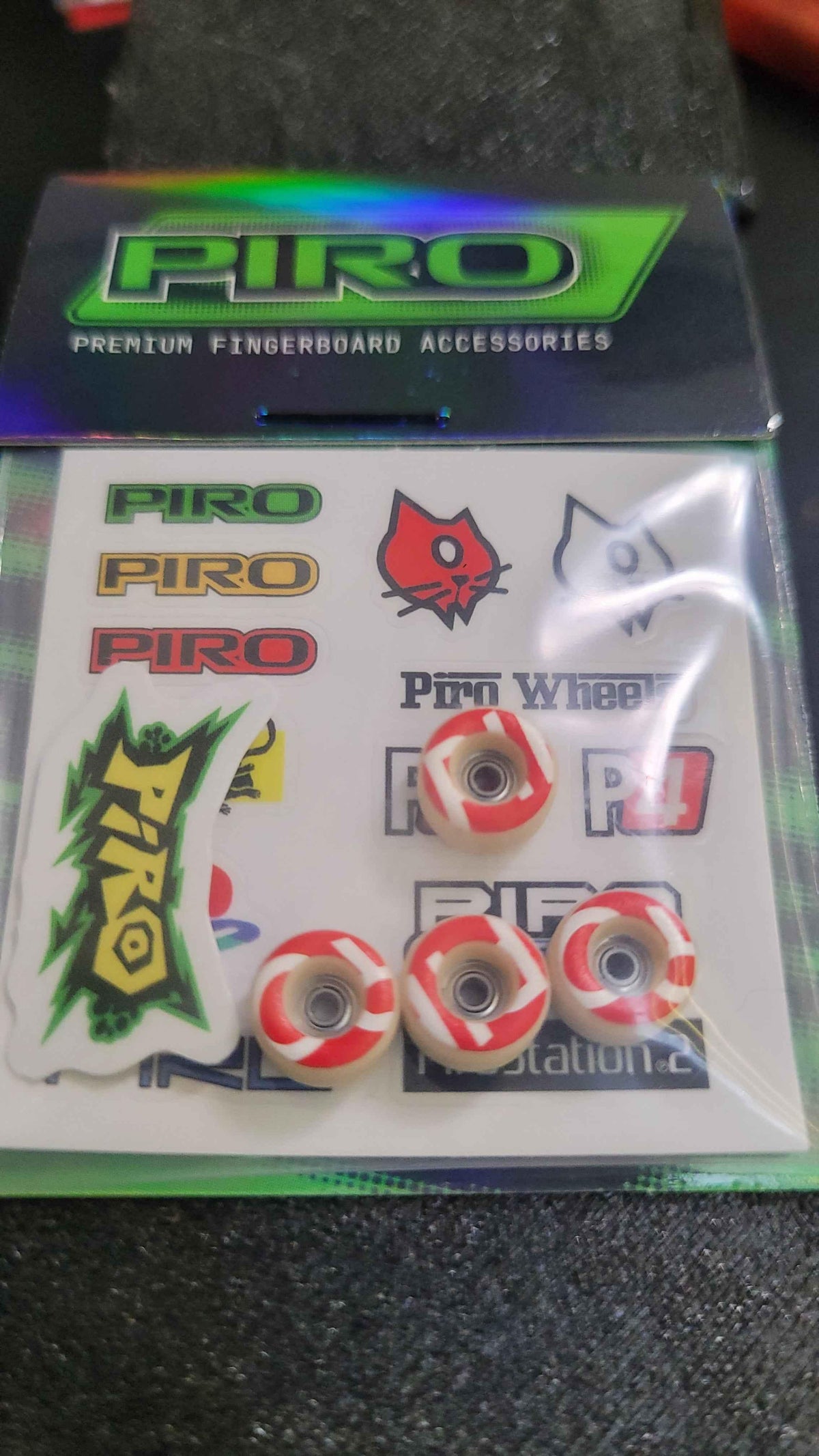 Piro fingerboard accessory kit with red and white wheels and branded stickers.