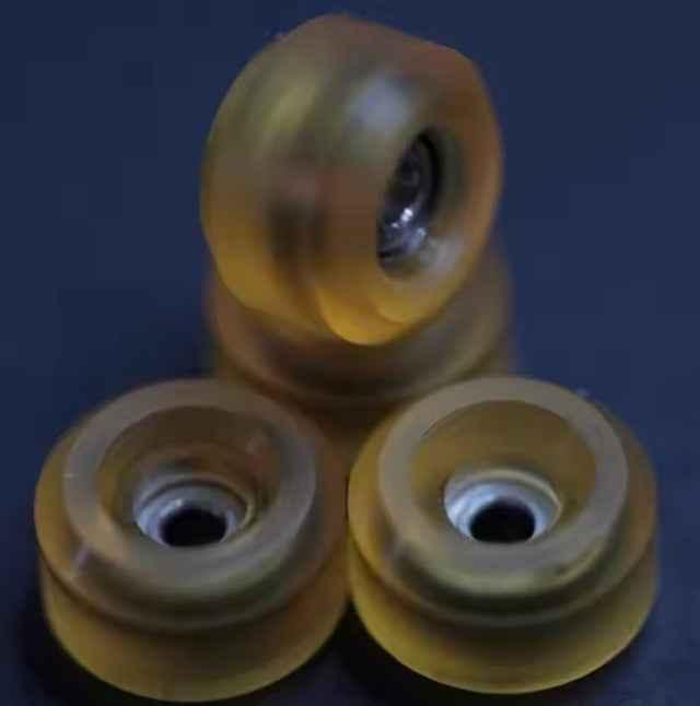 Three translucent yellow fingerboard wheels on a dark background