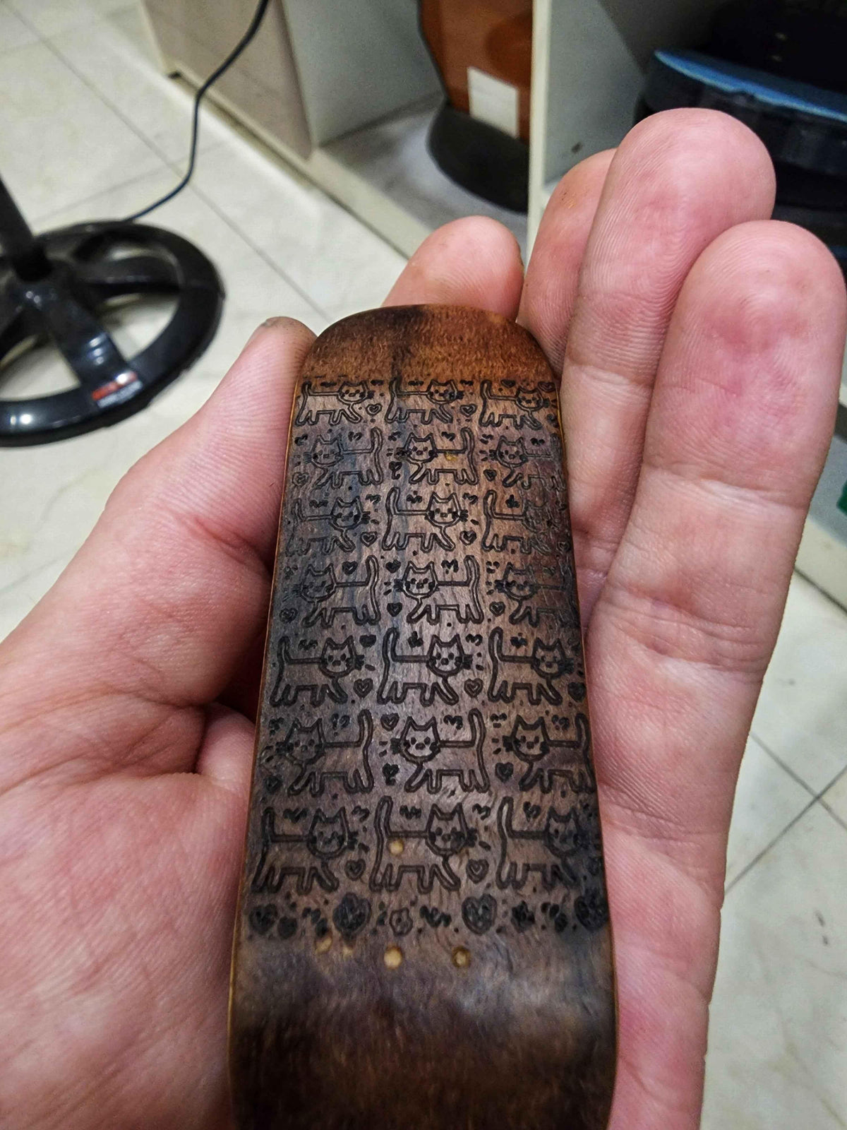 Handmade custom fingerboard deck with burned cat pattern design.
