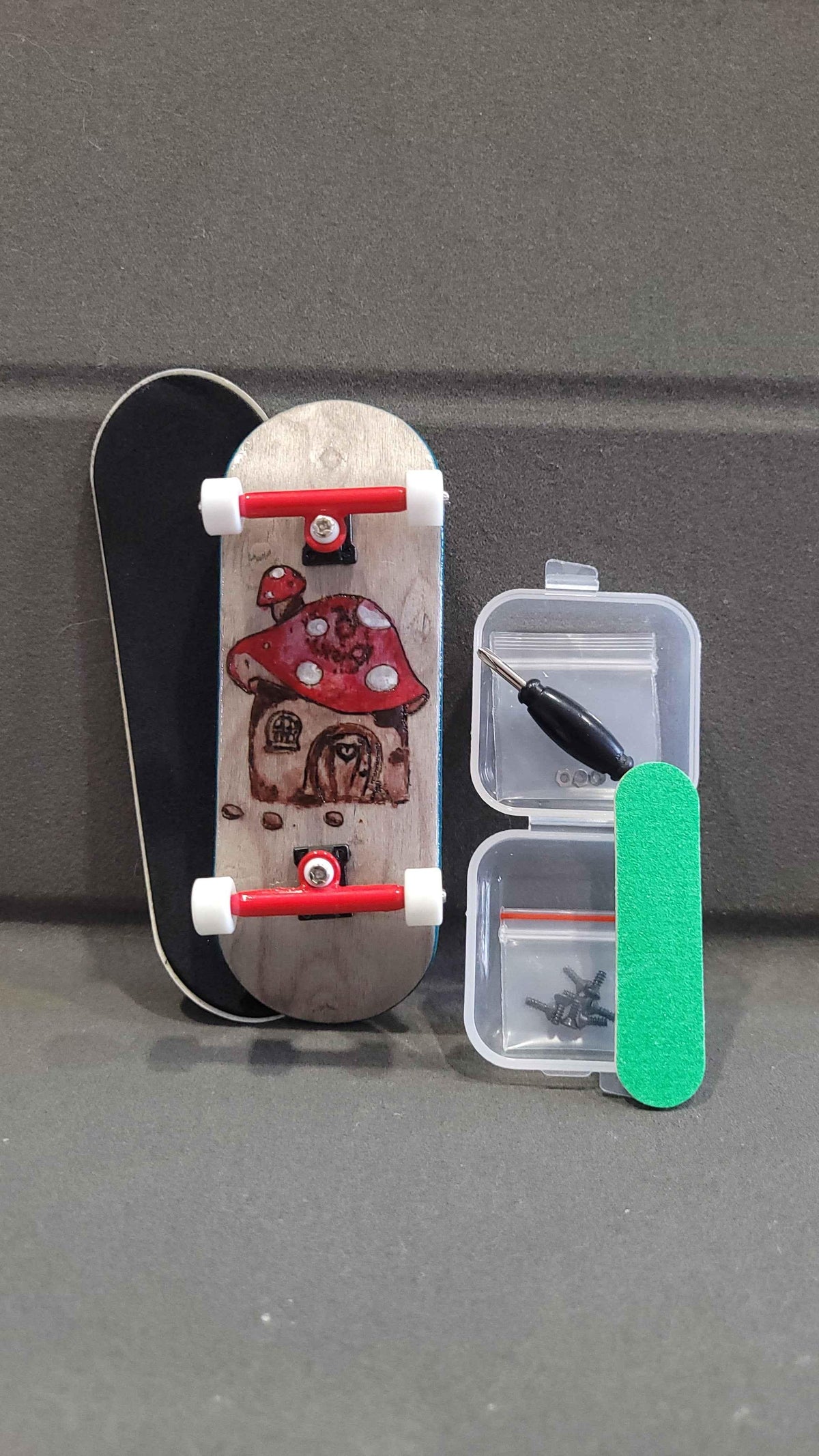 Custom handmade fingerboard deck with mushroom graphic, red trucks, and accessories.