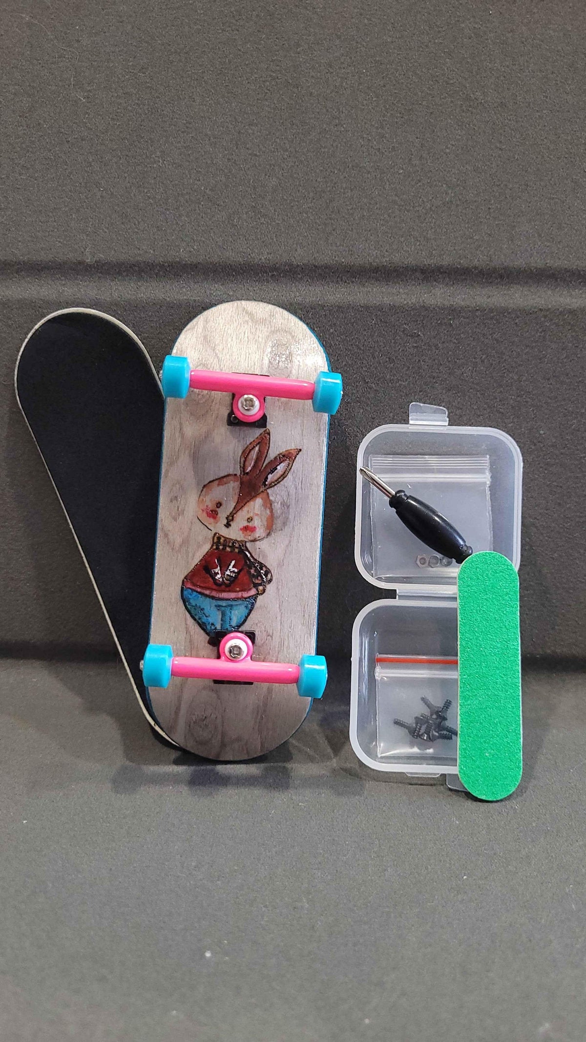 Custom fingerboard deck with bunny graphic, blue trucks, and miniature skate tools.