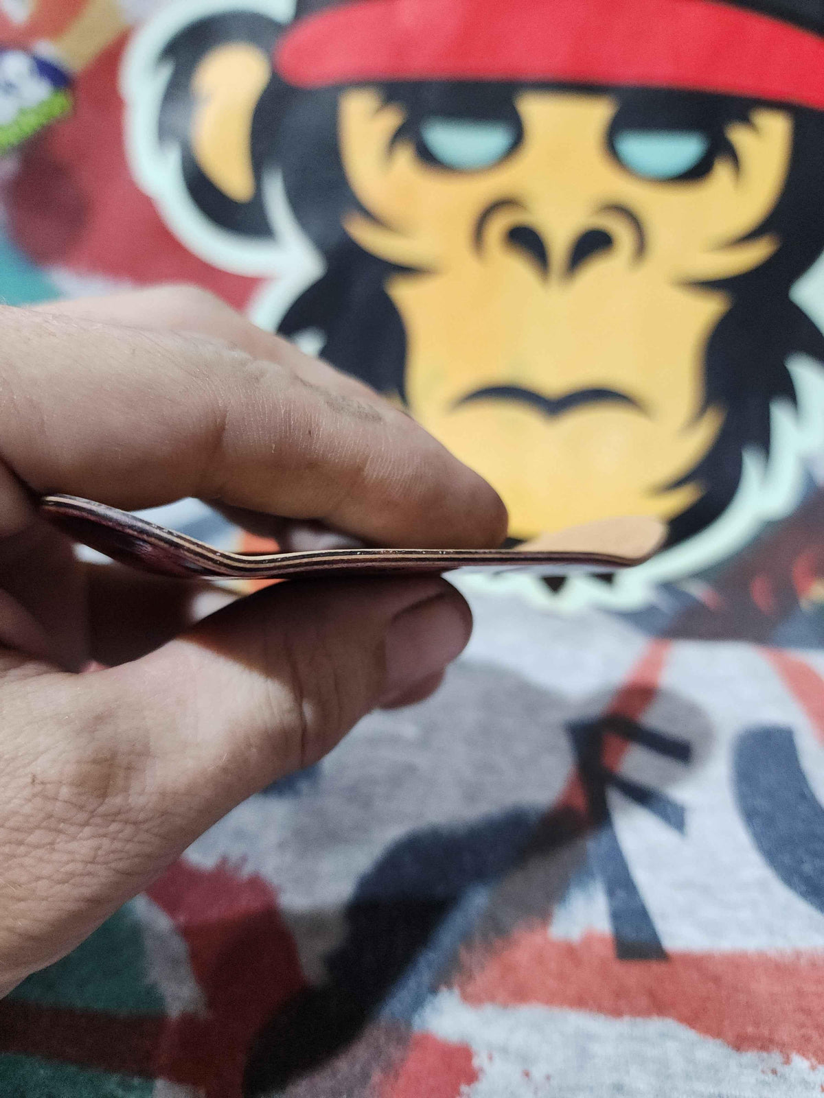 Close-up of a hand holding a thin, custom fingerboard deck.