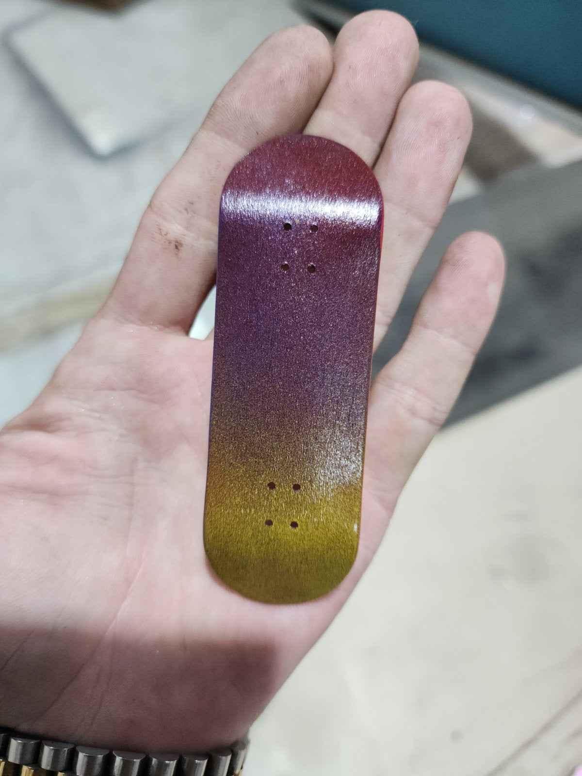 Handmade custom fingerboard deck with purple and yellow gradient glitter finish.
