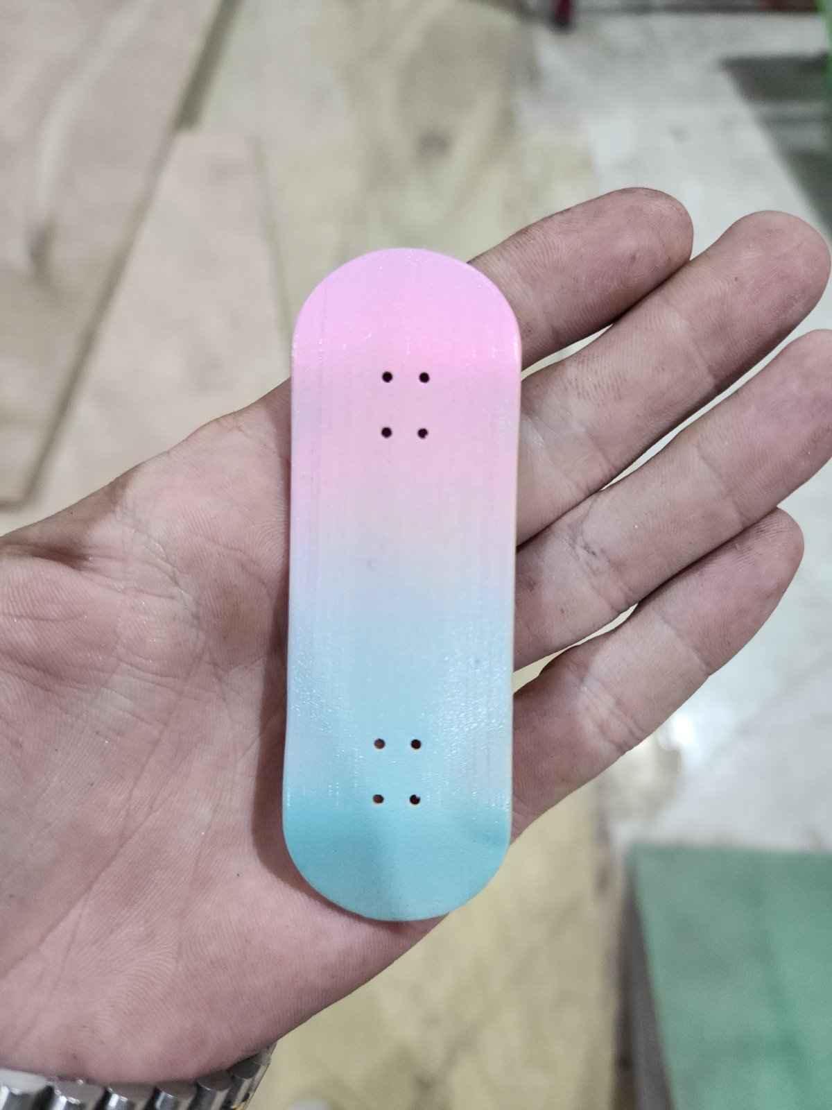 Handmade pink and blue gradient custom fingerboard deck held in a hand