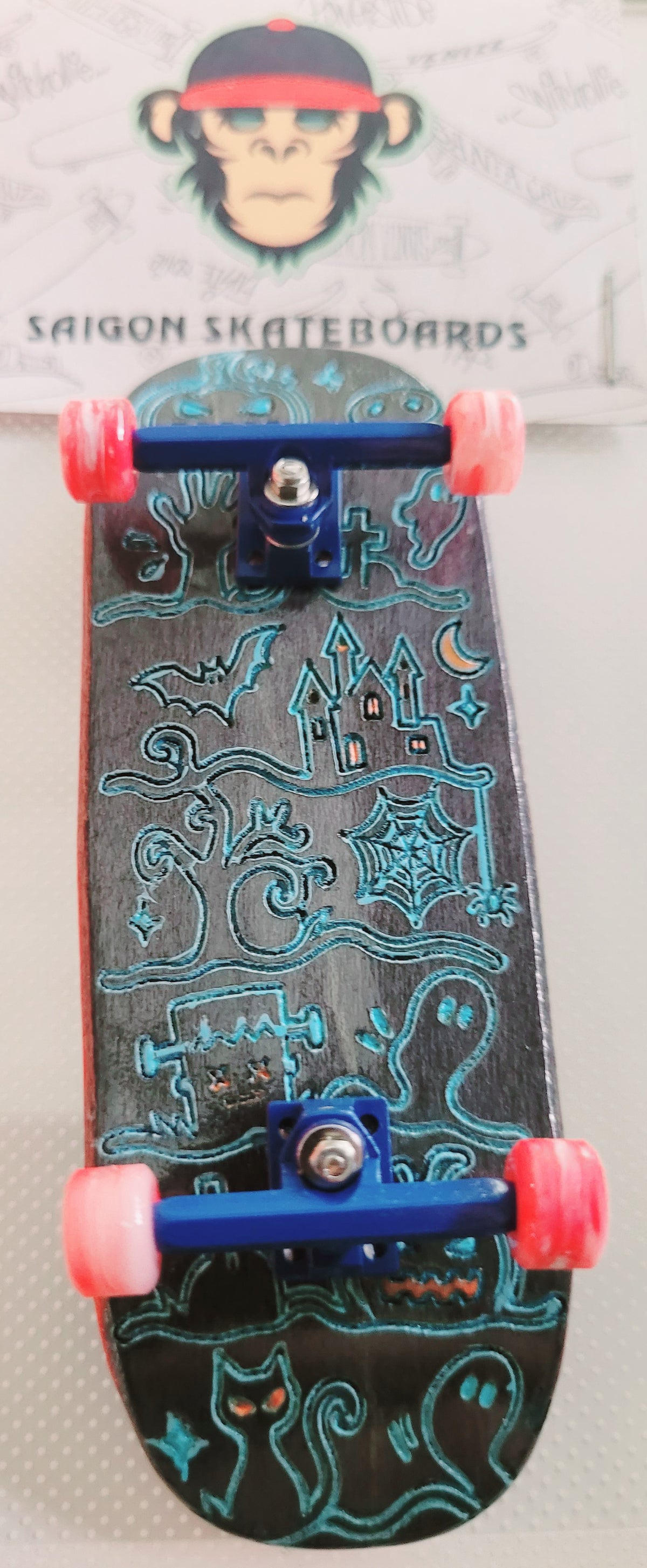 Skateboard deck with blue Ghost Town artwork and mounted trucks with red wheels