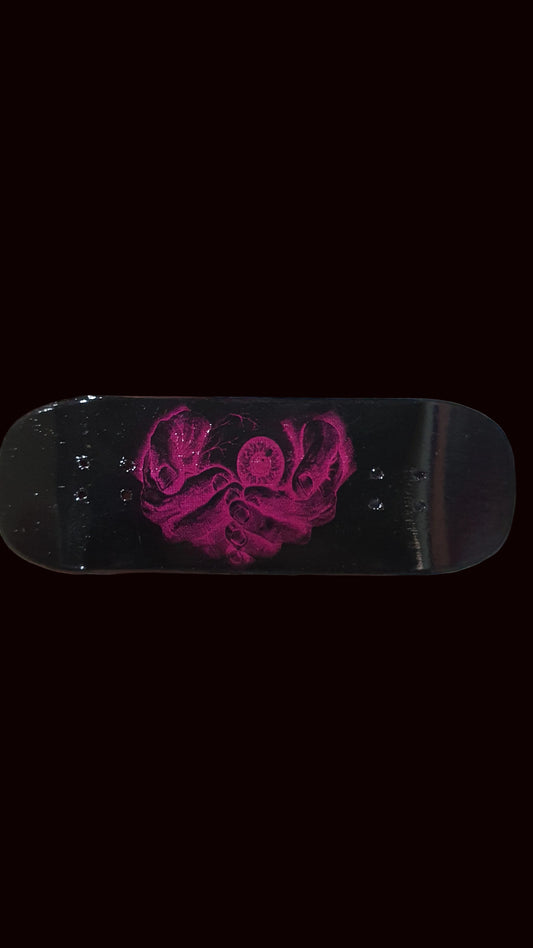 Black skateboard deck with a purple graphic in the center, close-up view.