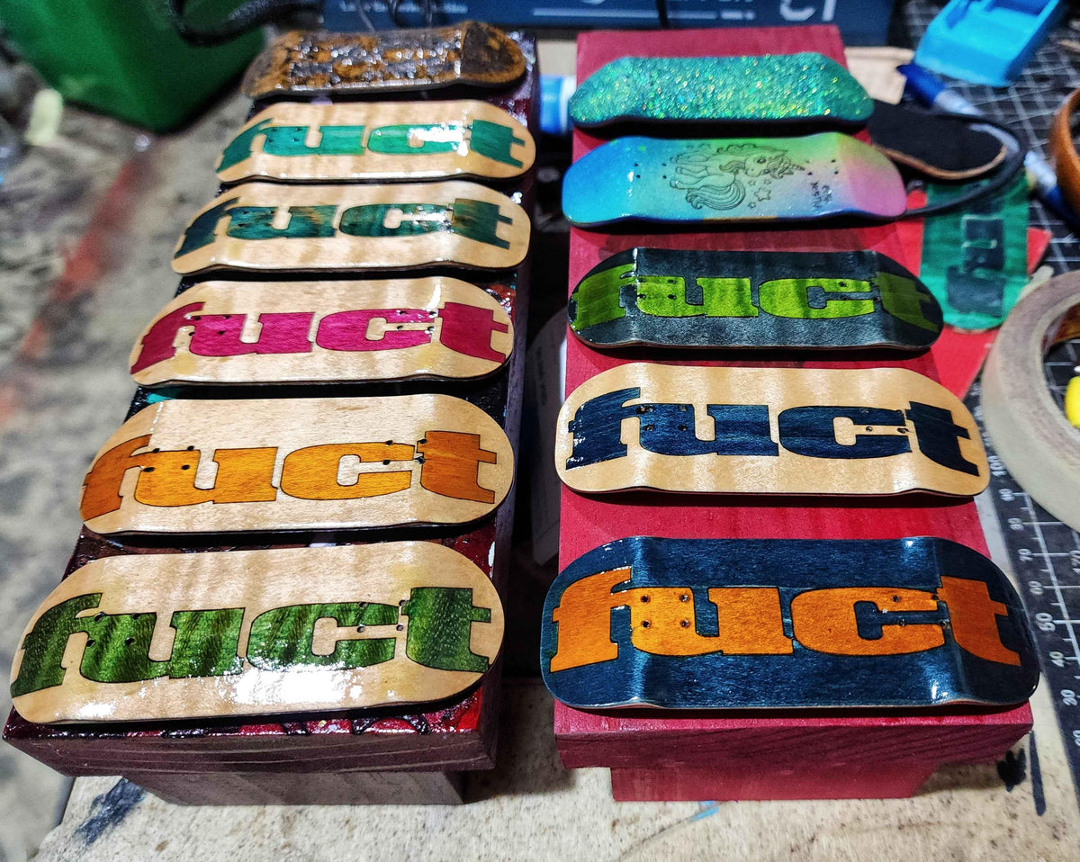 A collection of custom handmade fingerboard decks with colorful Fuct branding.