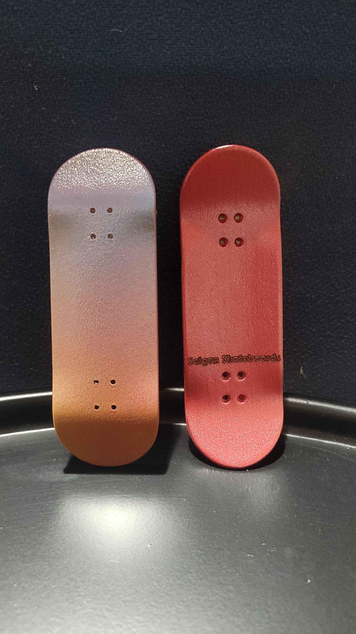 Two custom handmade fingerboard decks with gradient red and brown finishes.