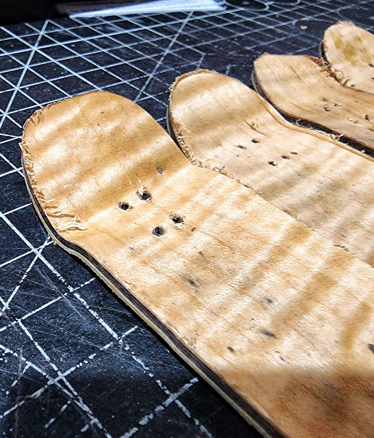 Handmade wooden fingerboard decks on a black cutting mat.