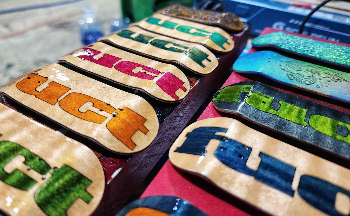 Handmade custom fingerboard decks with colorful graphic designs on a wooden display.
