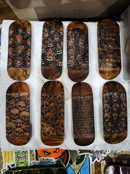 Collection of handmade custom wooden fingerboard decks with various dark artistic graphics.