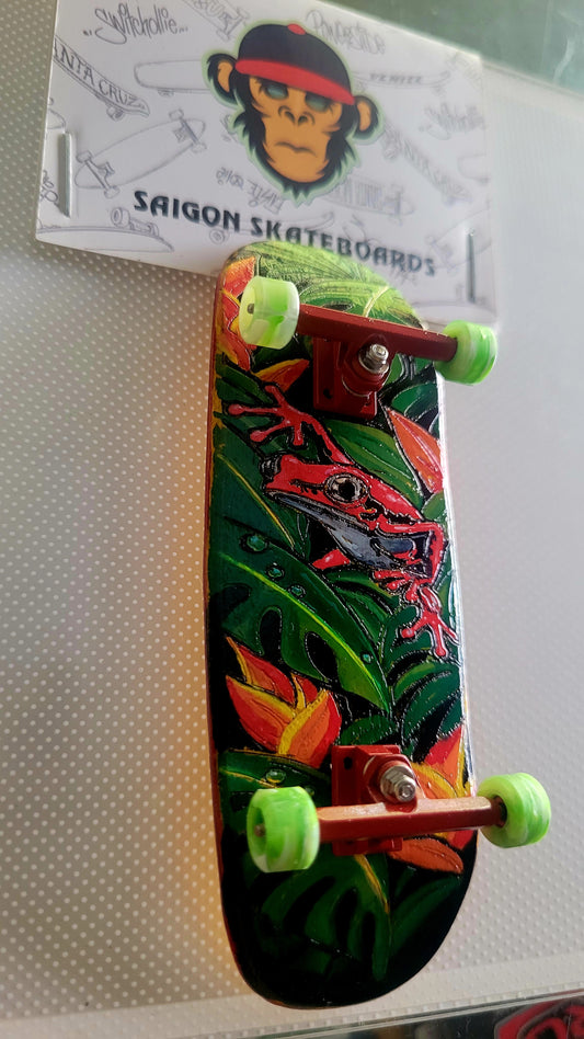 Green jungle fingerboard deck with red lizard art and lime wheels, angled view