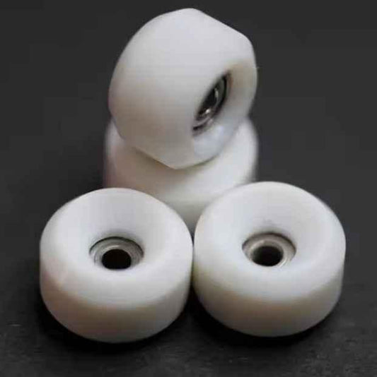 Four white fingerboard wheels with metal bearings on a dark background