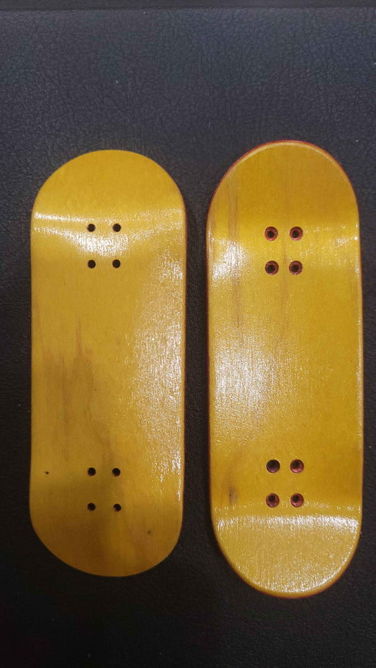 Two handmade wooden fingerboard decks with a natural glossy finish.