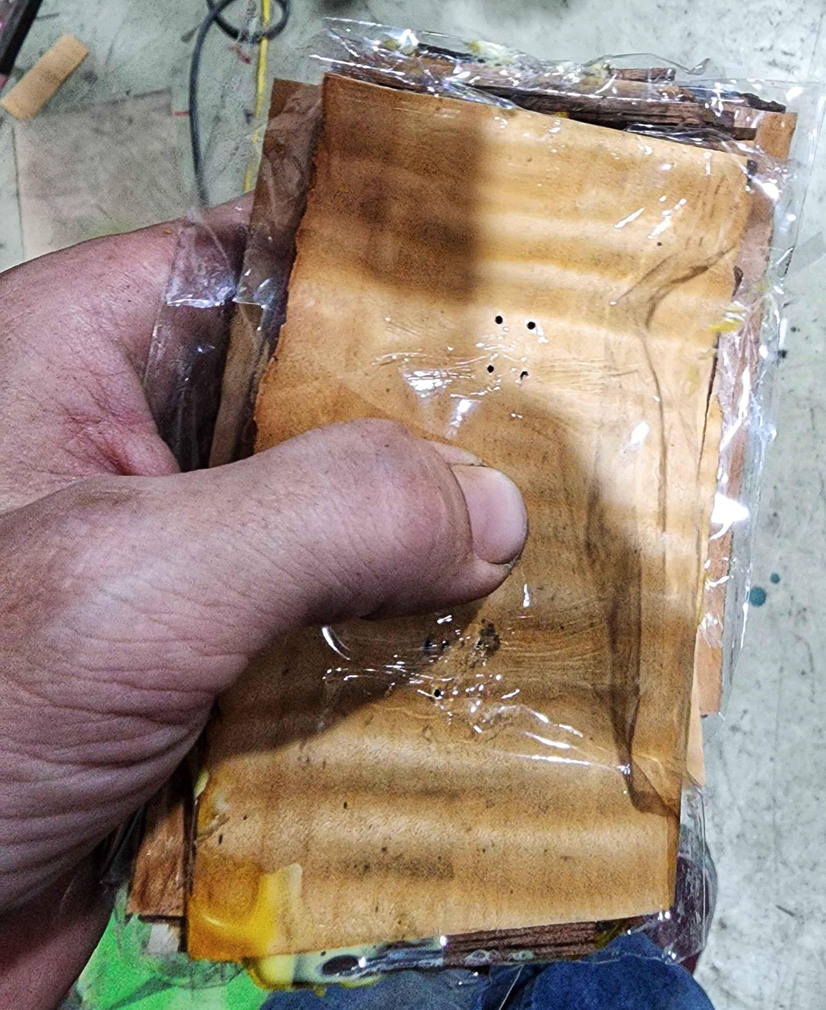 Hand holding a stack of handmade wooden fingerboard decks in plastic packaging.