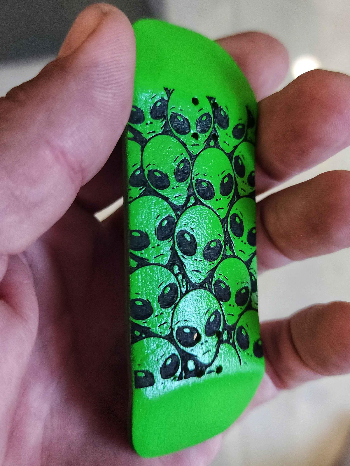 Custom green fingerboard deck featuring a black alien head graphic pattern.