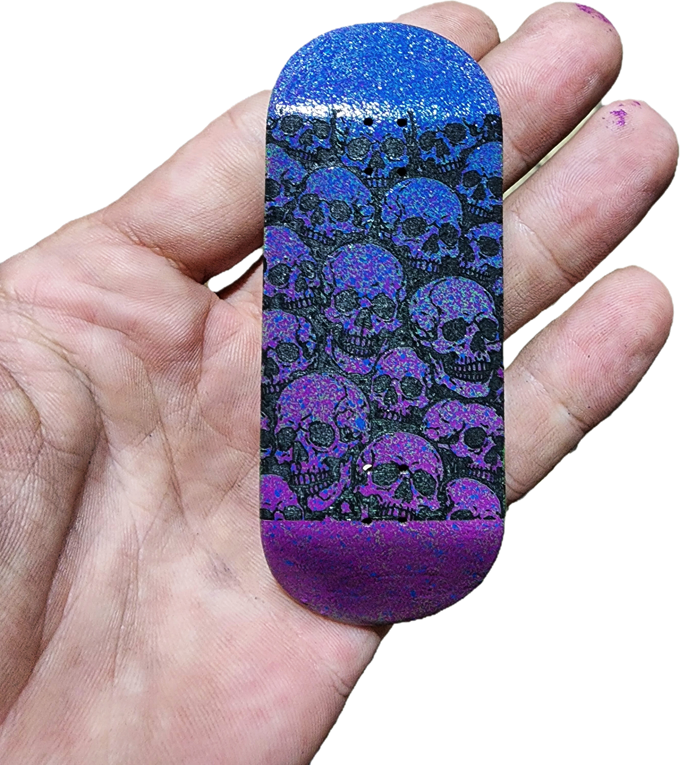 Blue and purple glittery object with black skull pattern held in a hand
