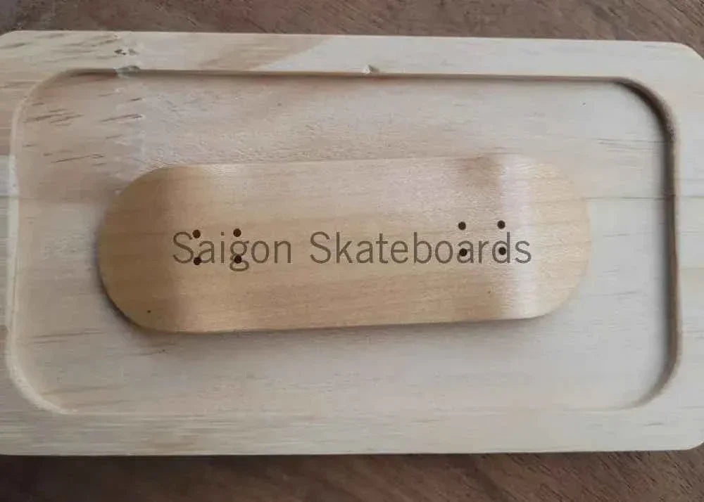 Handmade wooden fingerboard deck with Saigon Skateboards logo in a wooden tray