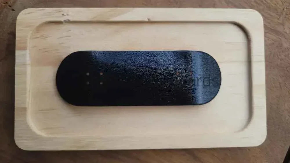 Black custom fingerboard deck resting on a light wooden tray