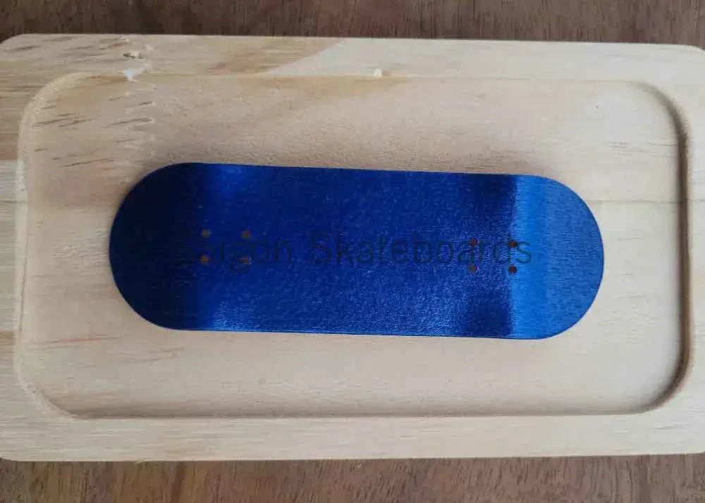 Blue custom fingerboard deck resting on a light-colored wooden tray