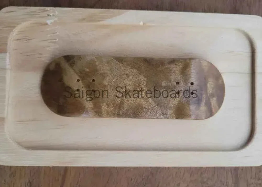 Handmade wooden fingerboard deck resting inside a light-colored wooden mold