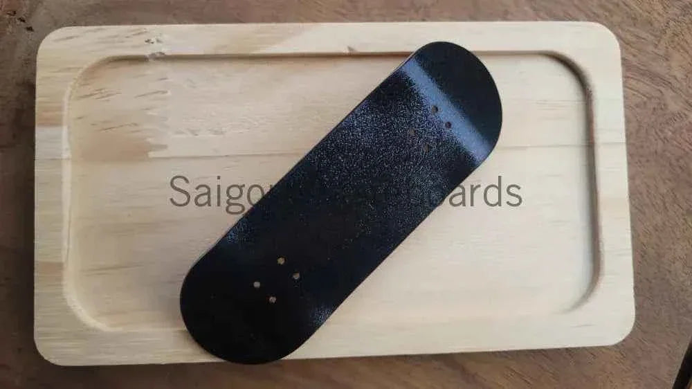 Black custom fingerboard deck resting on a light wood tray
