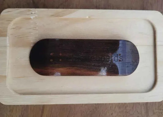 Handmade wooden fingerboard deck resting in a light wood display tray