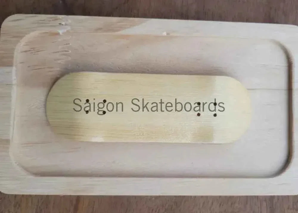 A handmade wooden fingerboard deck with Saigon Skateboards branding in a wooden case.