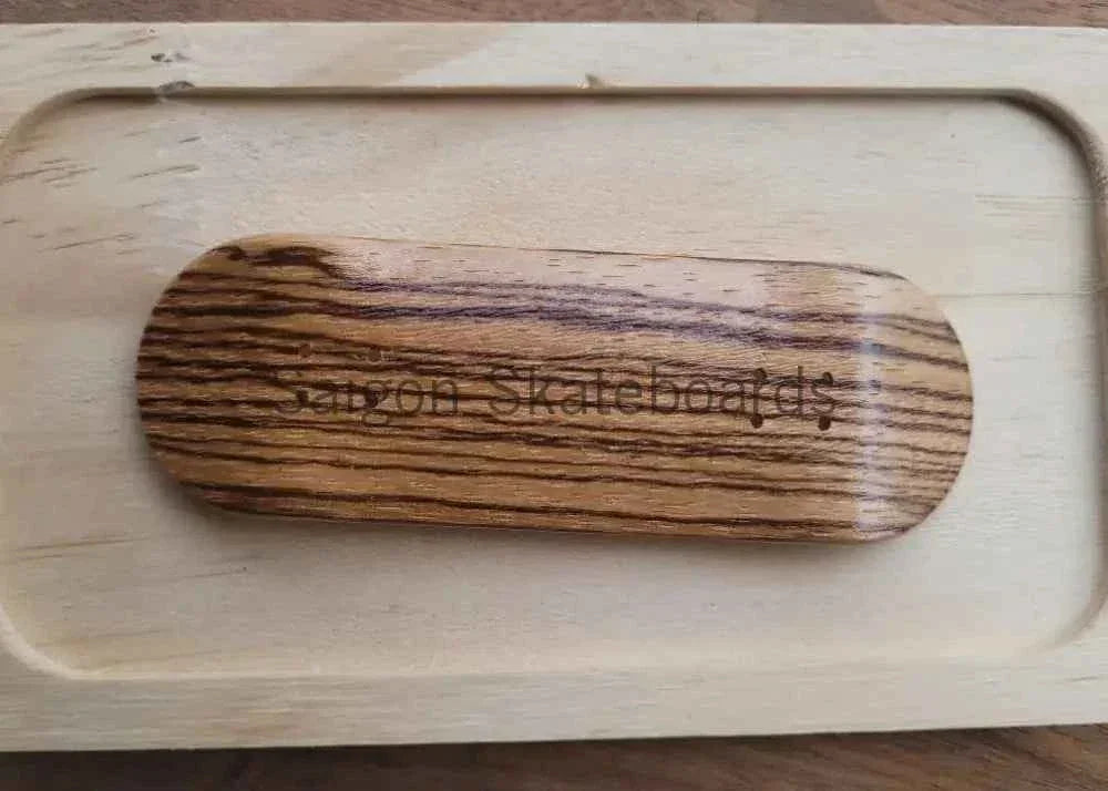 Handmade wooden fingerboard deck with grain texture resting on a wooden tray.