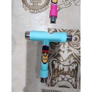 Light blue custom fingerboard truck with character graphic on a wooden surface.