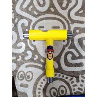 Yellow T-tool fingerboard tool with character graphic on a patterned surface