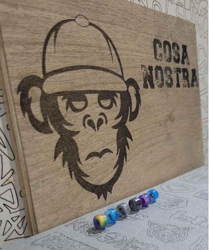 Laser-engraved wooden fingerboard deck featuring a monkey in a cap and 'COSA NOSTRA' text.