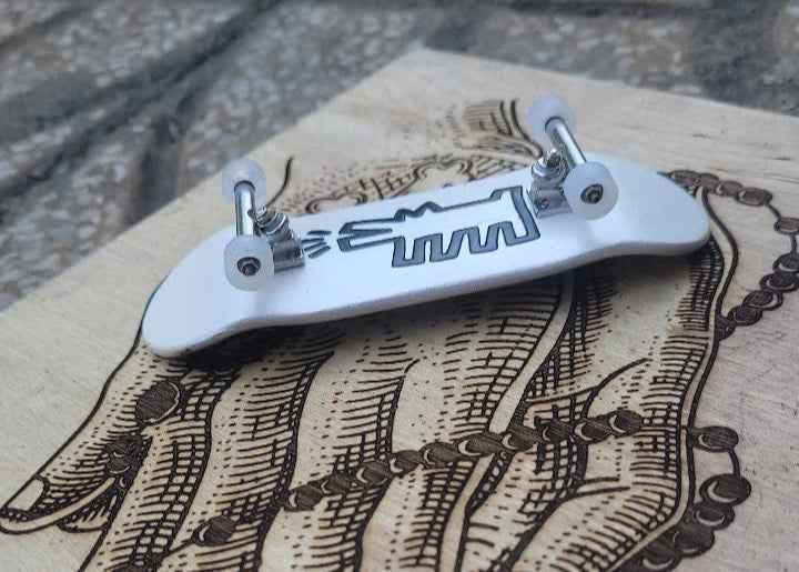 White custom fingerboard deck with silver trucks and small wheels on a wooden surface.