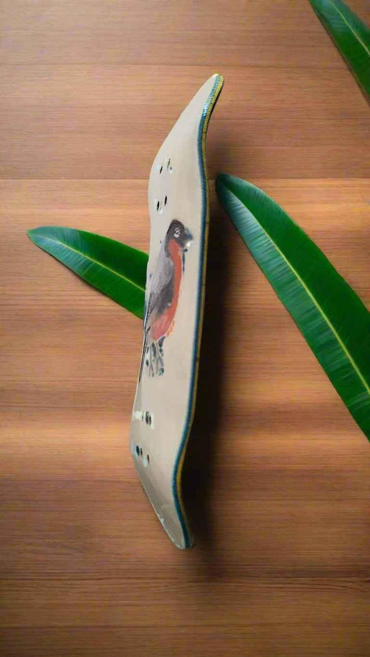 Handmade fingerboard deck with a red bird illustration on a wooden surface with green leaves.