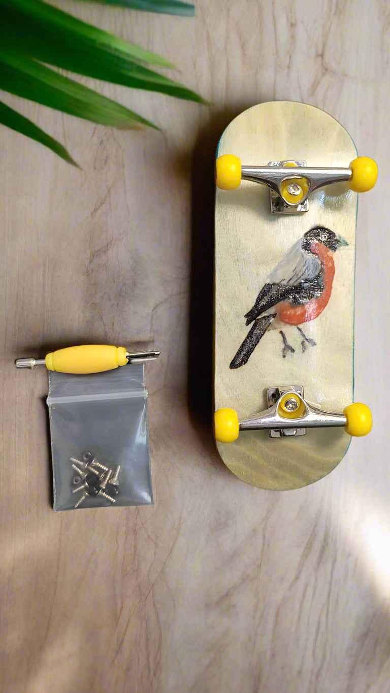 Custom handmade fingerboard with bird graphic, yellow wheels, and assembly tools.