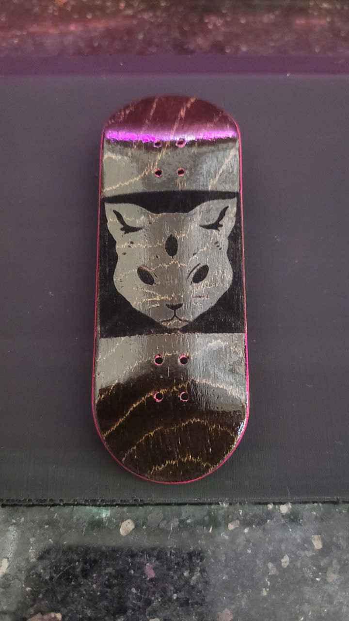 Handmade fingerboard deck featuring a stylized cat graphic on a wood grain surface
