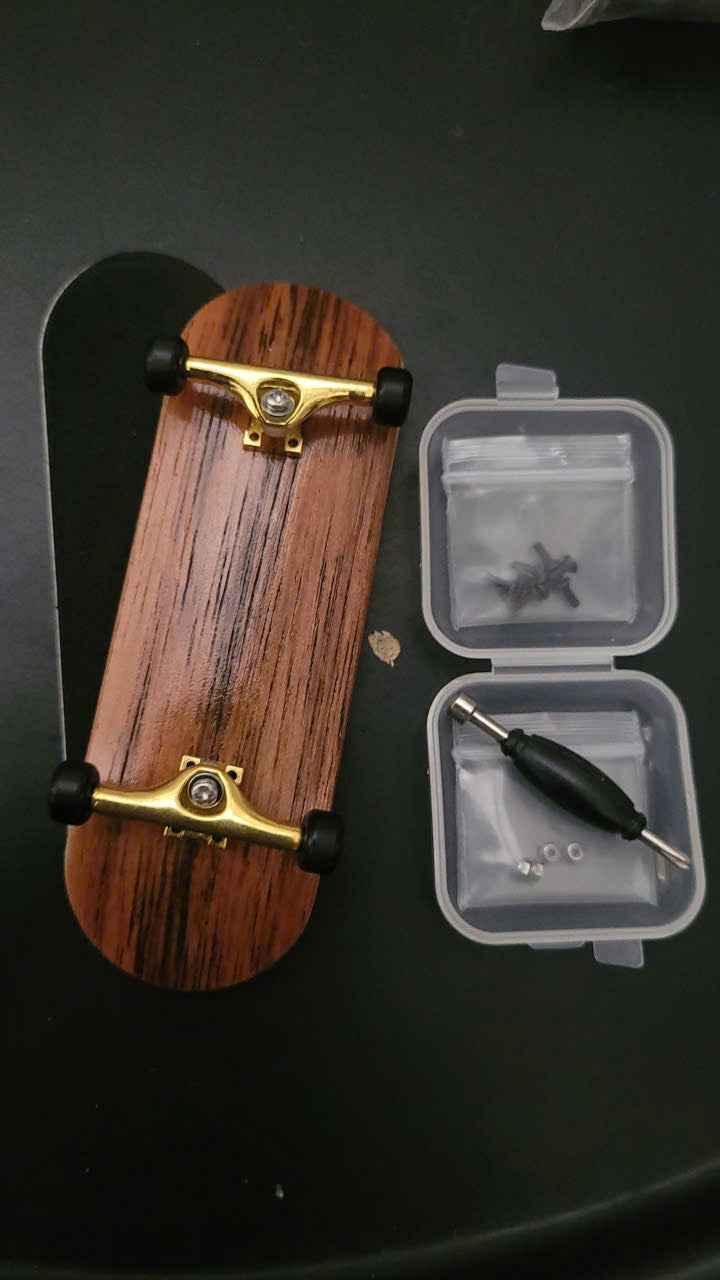 Custom wooden fingerboard deck with gold trucks and mini tool kit accessories.