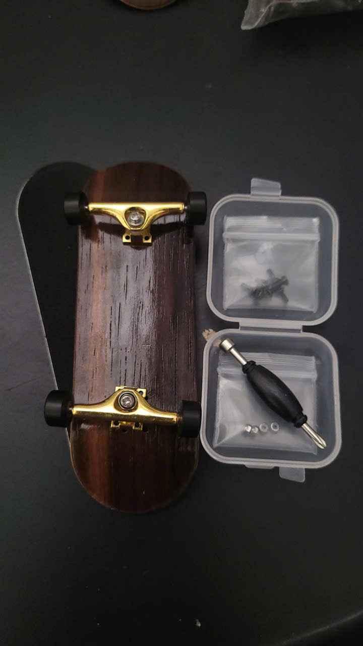 Custom wooden fingerboard deck with gold trucks and miniature skateboard tools.