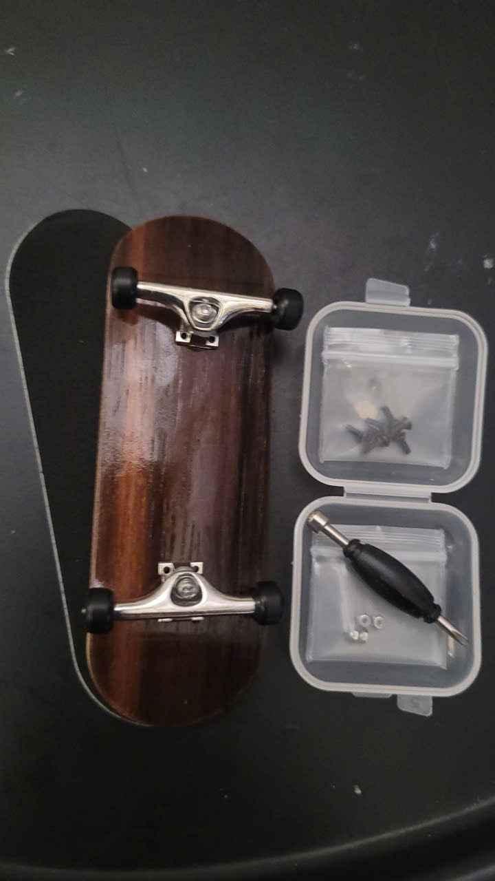 Handmade wooden fingerboard deck with silver trucks, wheels, and assembly tool kit.