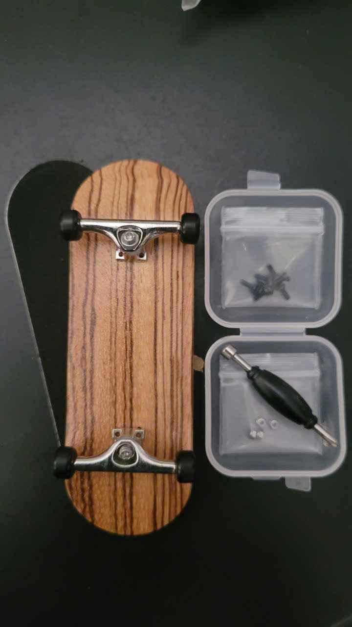 Custom wooden fingerboard deck with silver trucks, black wheels, and assembly tools.