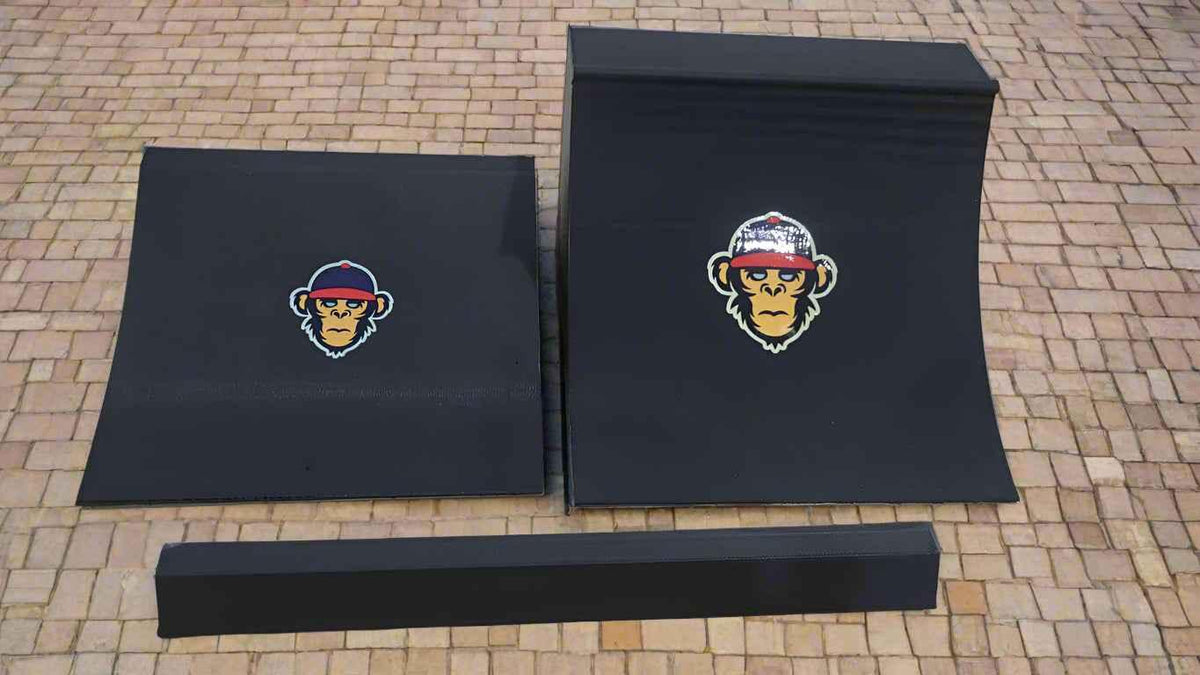 Black fingerboard obstacle set featuring a flat ledge and curved ramp with monkey logo decals.