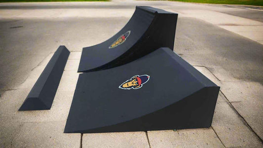 Black fingerboard mini ramps and a grind rail on a concrete surface.