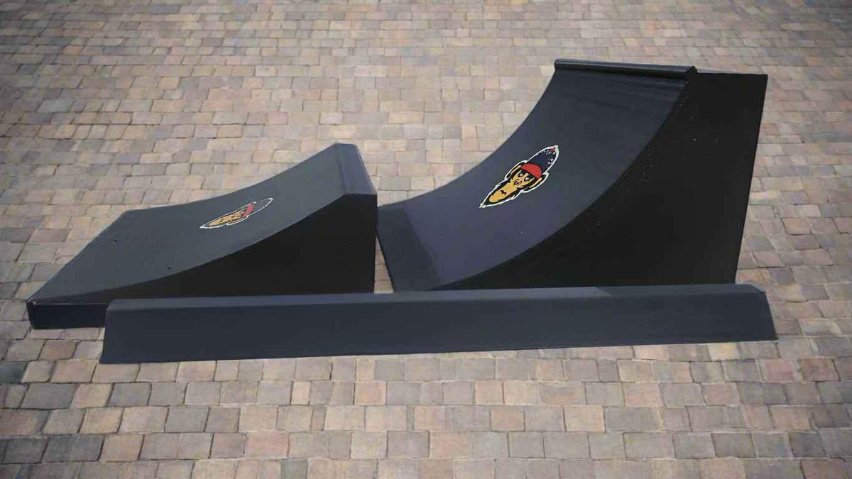 Black miniature fingerboard skate park ramp set with a quarter pipe and grind rail on pavers.