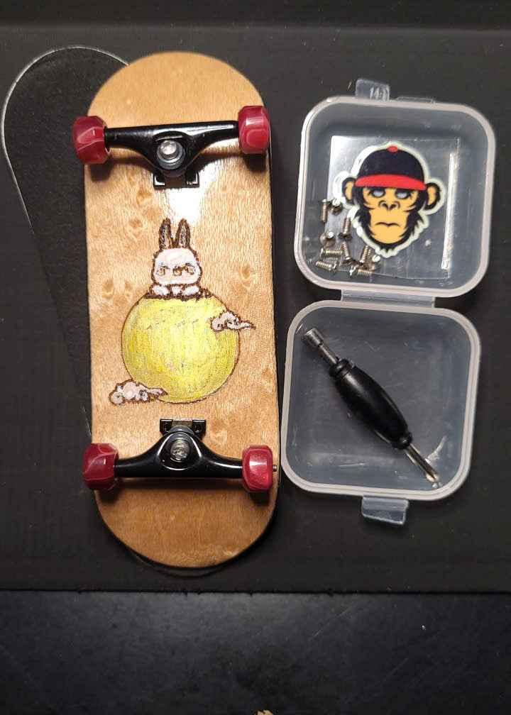 Custom handmade fingerboard with bunny graphic, trucks, wheels, and mini screwdriver kit.
