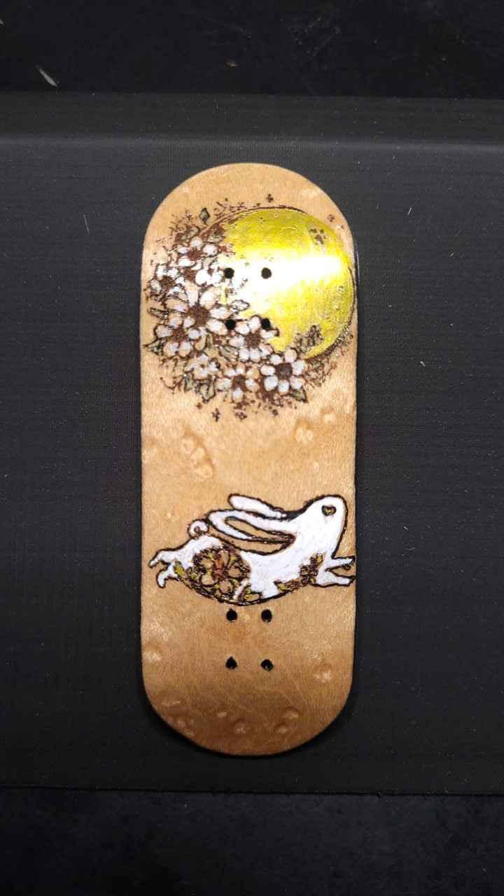 Handmade custom fingerboard deck with floral moon and white rabbit graphic.