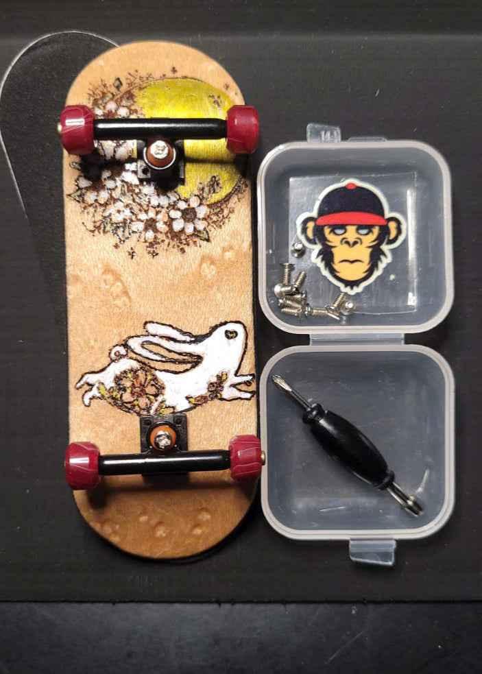 Custom handmade fingerboard deck with rabbit graphic and mini tool kit accessories.