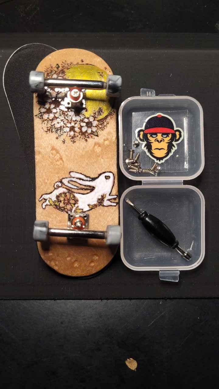 Custom handmade fingerboard deck with floral graphics and small tool kit in a plastic case.